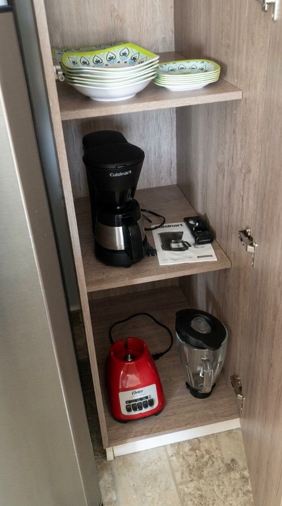 Kitchen cabinet with a coffee maker, carafe, plates, and blender in an El Rodadero Santa Marta apartment